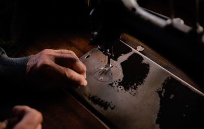 Cropped hands of tailor using sewing machine