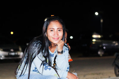 Portrait of smiling young woman on illuminated street at night