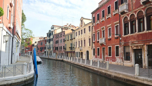 Canal amidst buildings against sky in city