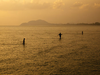 Silhouette people in sea  during sunset