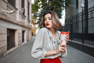 Beautiful young woman using phone while standing in city
