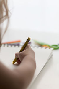 Cropped image of child painting on book with crayon