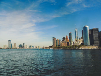 Modern cityscape by river against sky