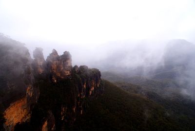 Scenic view of blue mountains in foggy weather against clear sky