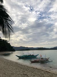 Sailboats moored on beach against sky