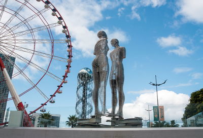 Low angle view of ferris wheel against cloudy sky