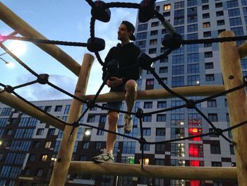 Low angle view of man jumping in city against sky