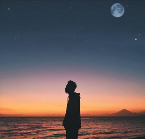 Silhouette man standing by sea against sky at sunset