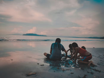 People on beach against sky during sunset