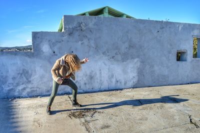 Full length of woman jumping against sky on sunny day