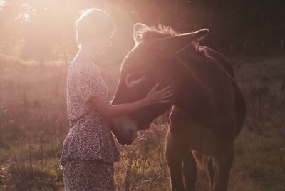 Rear view of woman with horse on field