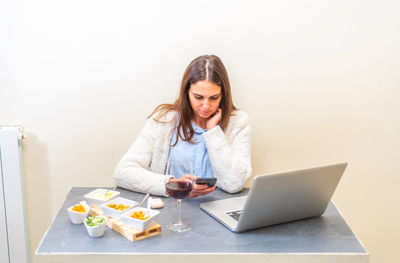 Young woman using mobile phone on table