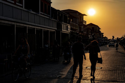 People walking on street in city at sunset