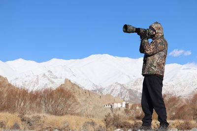 Rear view of woman standing on mountain against clear blue sky