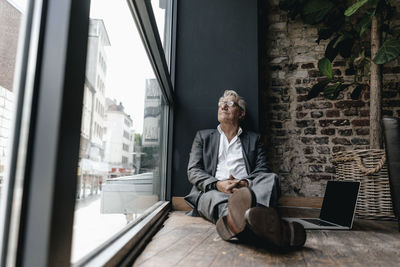 Businessman sitting on floor next to window, taking a break