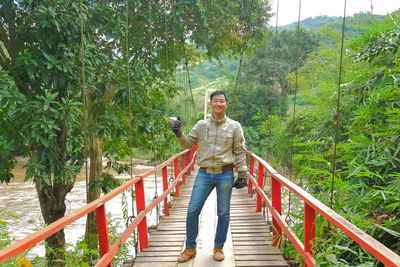 Portrait of man on footbridge against trees