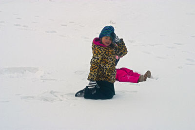 Girl playing on snow field during winter