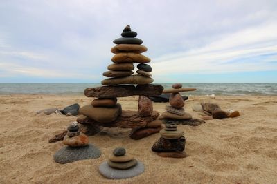 Stack of pebbles on beach against sky