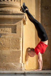 Full length of young man jumping against wall