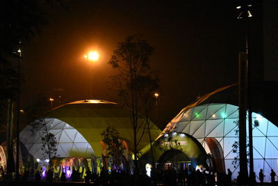 Crowd at illuminated city against sky at night