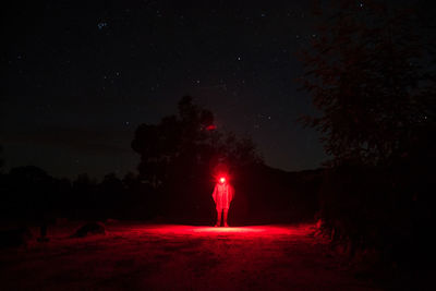 Person wearing illuminated headlamp while standing on footpath at night