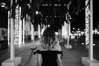 Rear view of woman standing at illuminated night