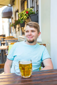 Portrait of smiling man sitting with drink on table