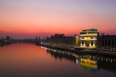 Reflection of illuminated buildings in lake during sunset