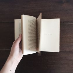 Cropped hand flipping pages of book at table