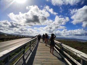 Rear view of people walking on footbridge