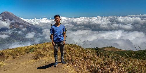 Portrait of man standing against cloudscape on mountain