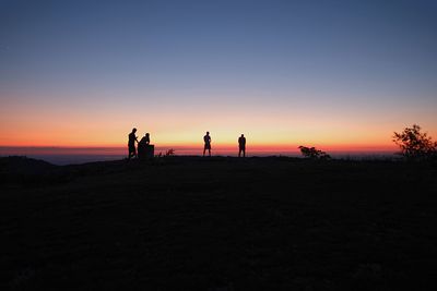 Silhouette people standing on shore against sky during sunset