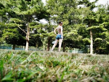 Surface level shot of woman holding badminton and shuttlecock while standing on grass