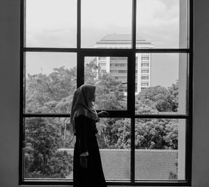 Side view of woman in hijab looking through window