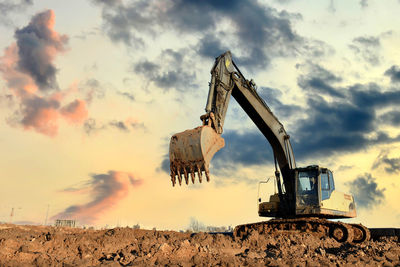 Crane at construction site against sky during sunset