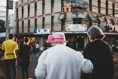 Rear view of people walking on street in city