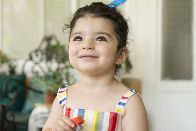 Close-up of cute baby girl looking away against built structure