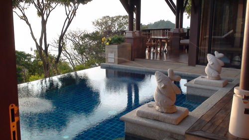 Fountain in swimming pool by trees against sky