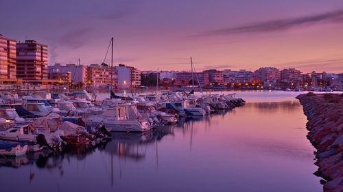 Boats moored at harbor against sky during sunset