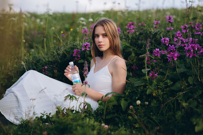 Beautiful young woman holding flower on field