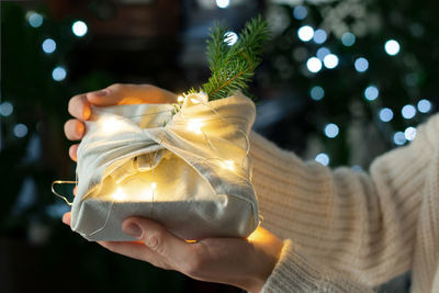 Christmas gift in hands. packaging in eco-friendly materials, furoshiki fabric.