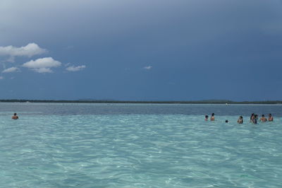 People swimming in sea against sky