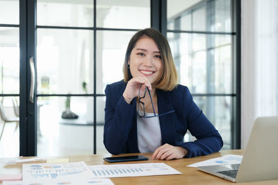 Portrait of a smiling young woman looking through window