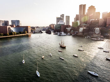 Boats in river by buildings against sky in city