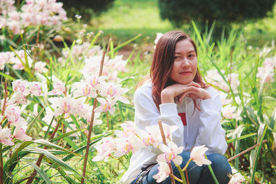 Young woman with hand on chin sitting at park