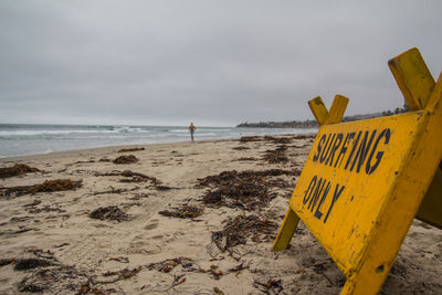 Information sign on beach against sky