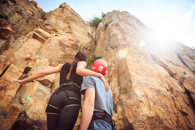 Low angle view of woman holding rock on mountain against sky