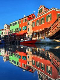 Buildings by canal against sky in city