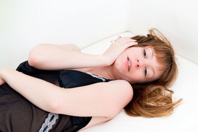 High angle portrait of woman lying against white background