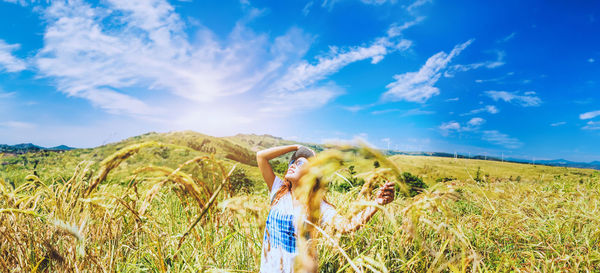 Rear view of woman standing on field against sky